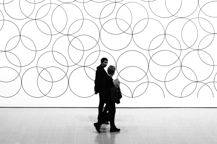 People walking in front of circles pattern painting
